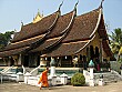 A monk walks by a wat in peaceful Luang Prabang.